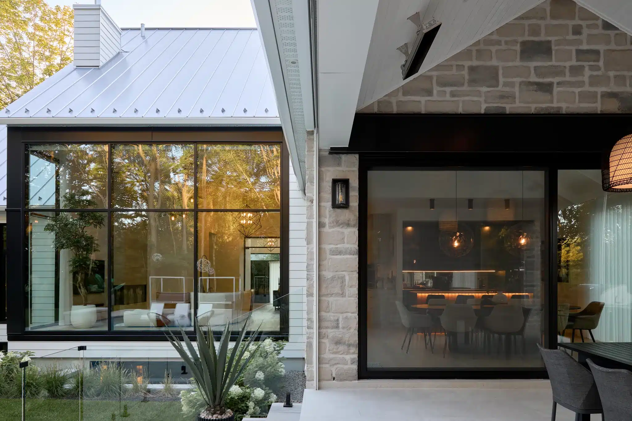 Terrasse couverte avec foyer extérieur en maçonnerie, à côté de la grande baie vitrée du salon.
