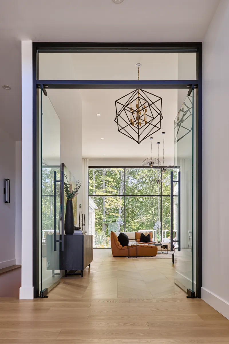 Vue depuis l’entrée vers le salon et la grande fenestration donnant sur la cour de la Maison S+J.